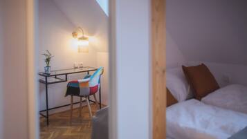 A cozy room with a bed, a desk with a chair, and a potted plant.