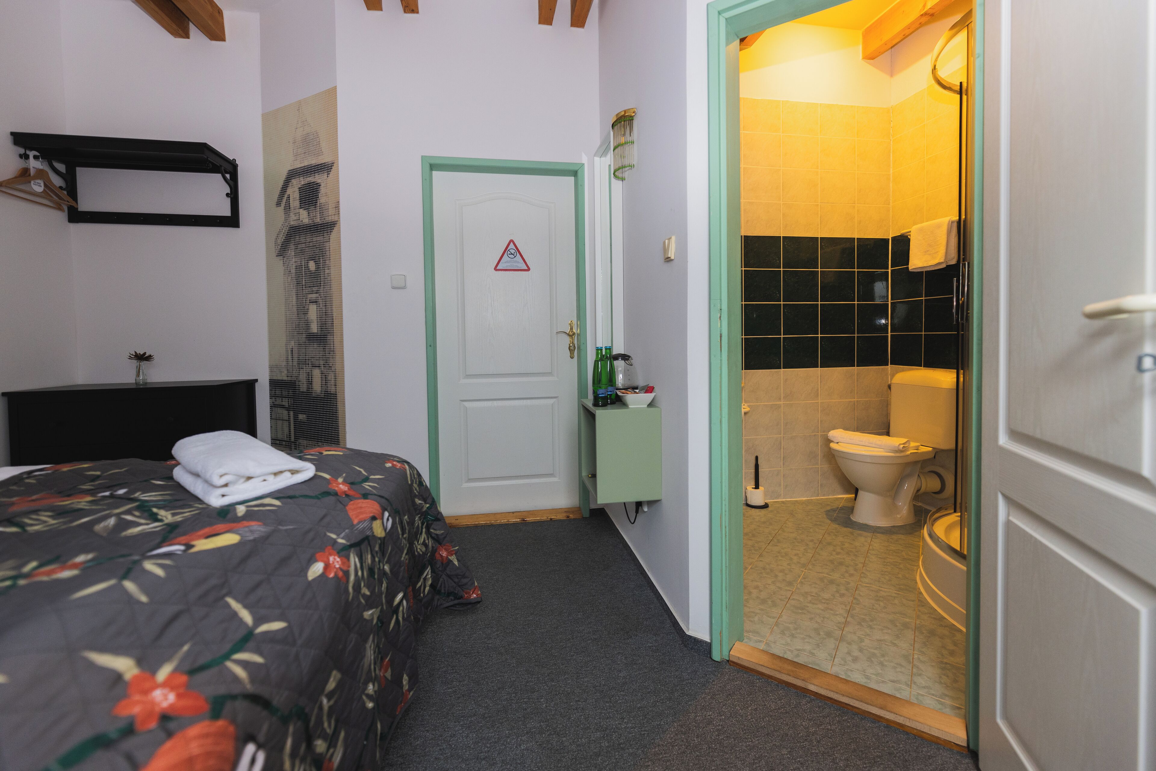 A hotel room with a bed, a bathroom with a toilet and sink, and a door with a warning sign.
