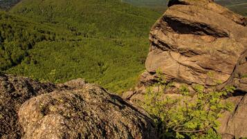 A rocky landscape with a prominent rock formation and a view of a forested valley.