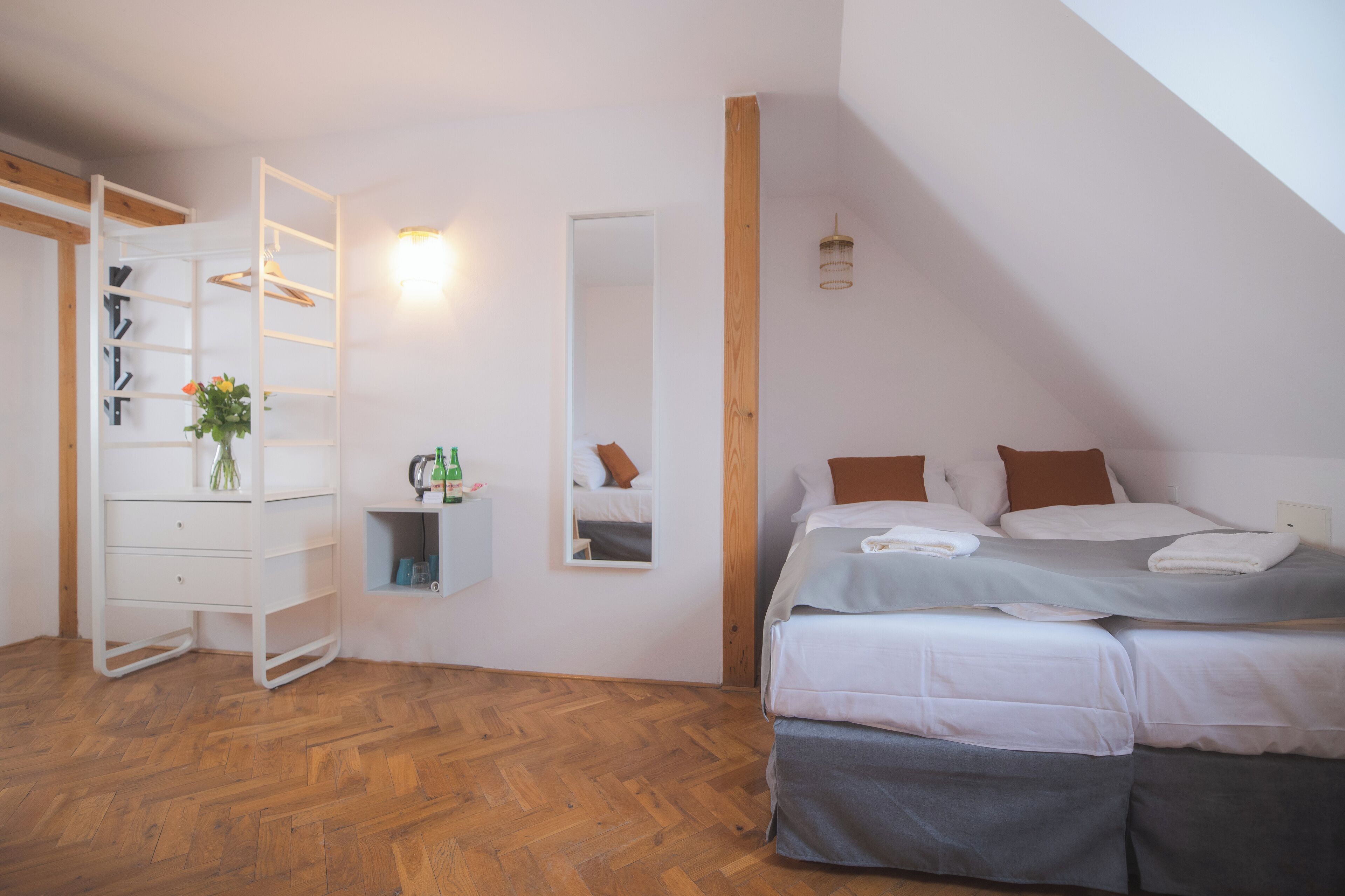 A bedroom with a loft bed, a white dresser, a mirror, and a wooden ceiling beam.