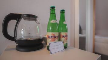 Eine transparente Kaffeekanne, zwei grüne Flaschen mit dem Aufdruck 'MATTON' und ein Schild mit Schrift in einer Fremdsprache.