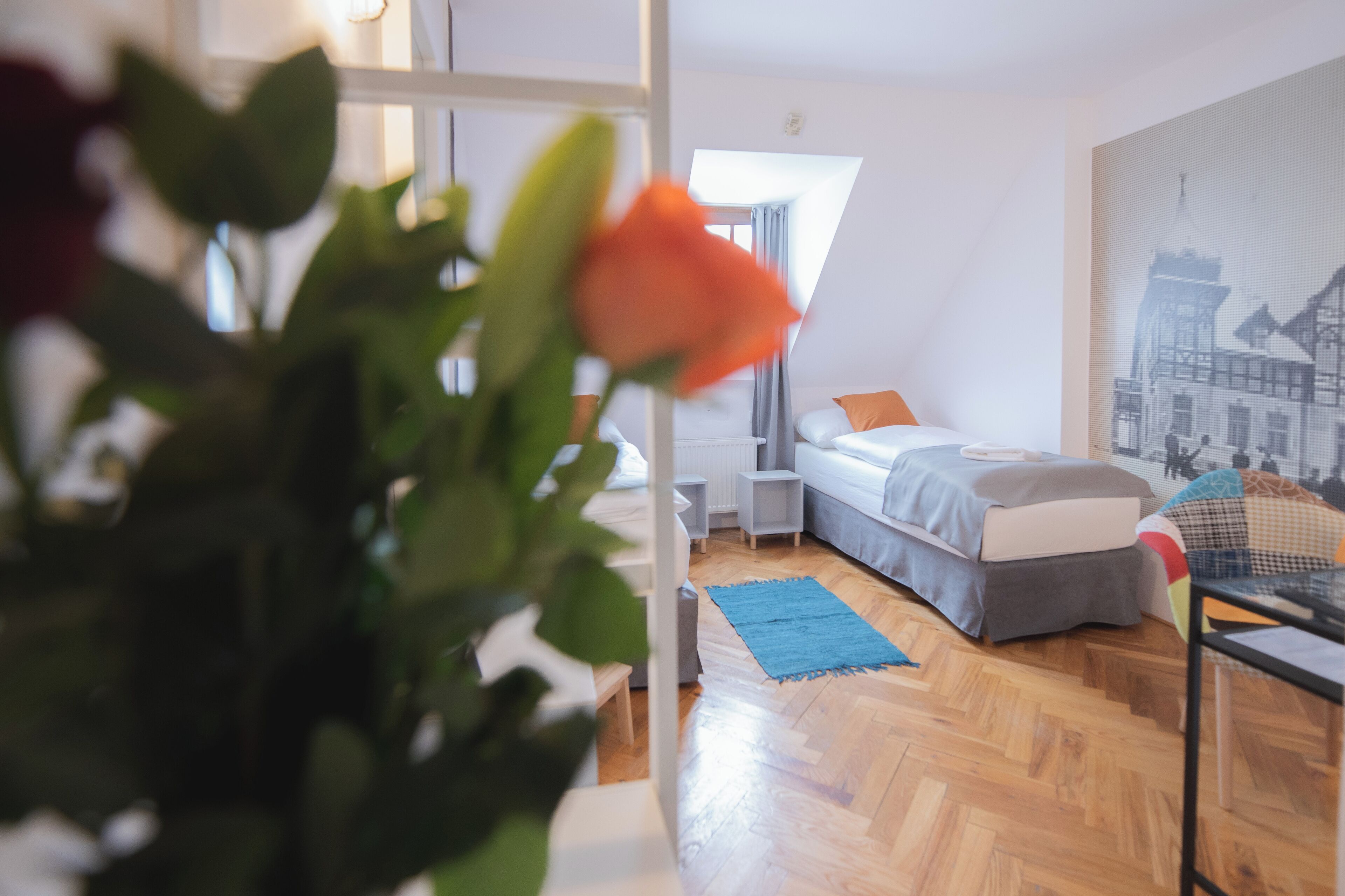 A modern bedroom with a bed, bedside tables, a blue rug, and a cityscape painting.