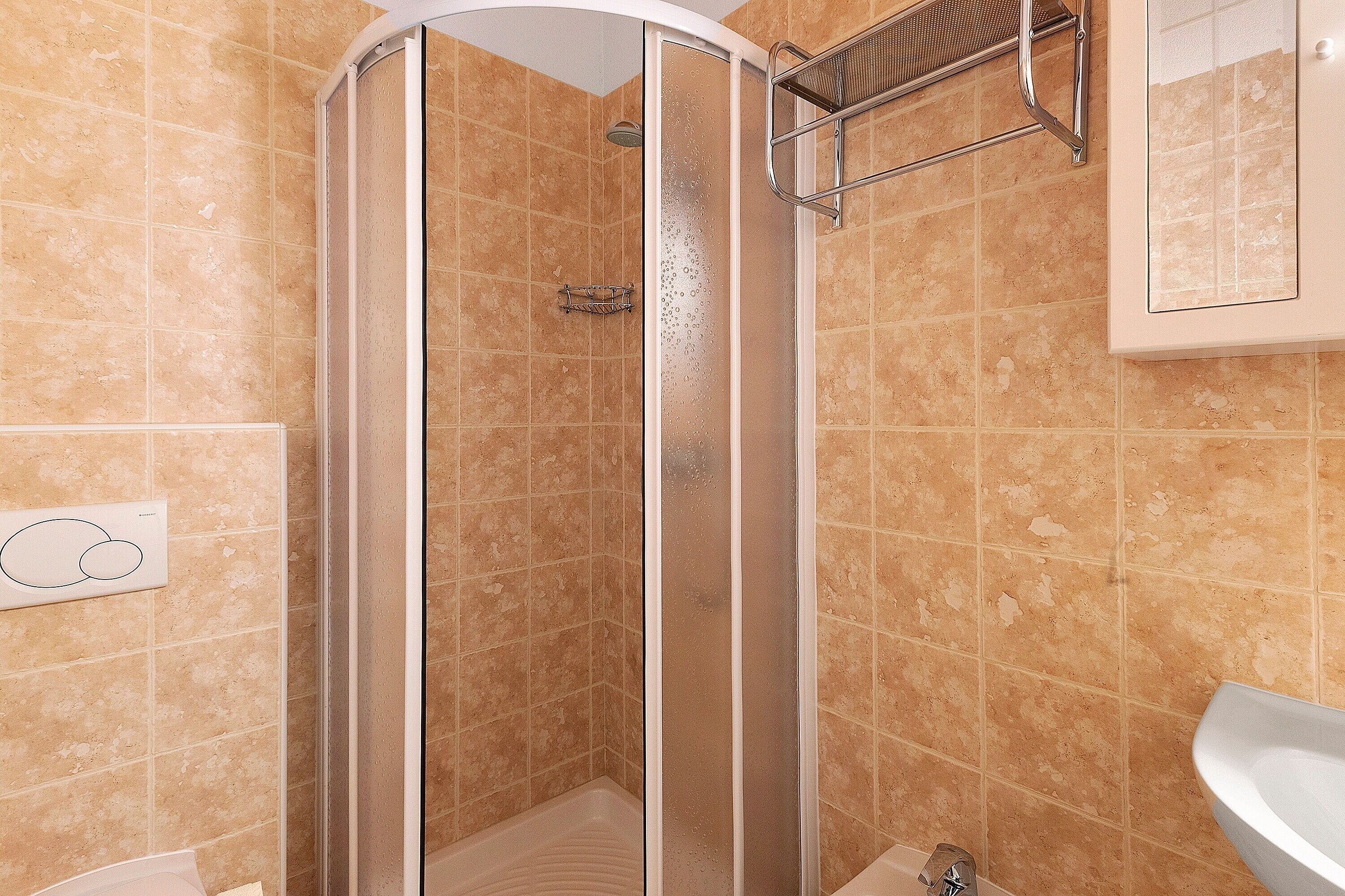 A shower with a glass door, a towel rack, and a sink.