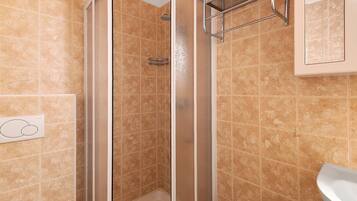 A shower with a glass door, a towel rack, and a sink.