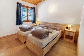 A wooden bed with two pillows, a nightstand, and a window with curtains. - Room 'Camera Matrimoniale' with Mountain View, Shared Garden and Wi-Fi (Grosio)