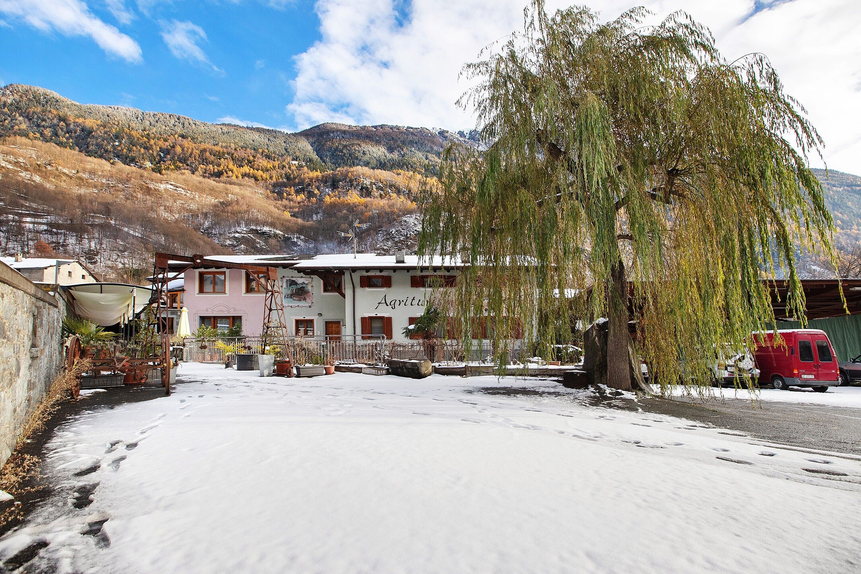 A building with a sign reading 'Agriturismo' in a snowy setting with mountains in the background.