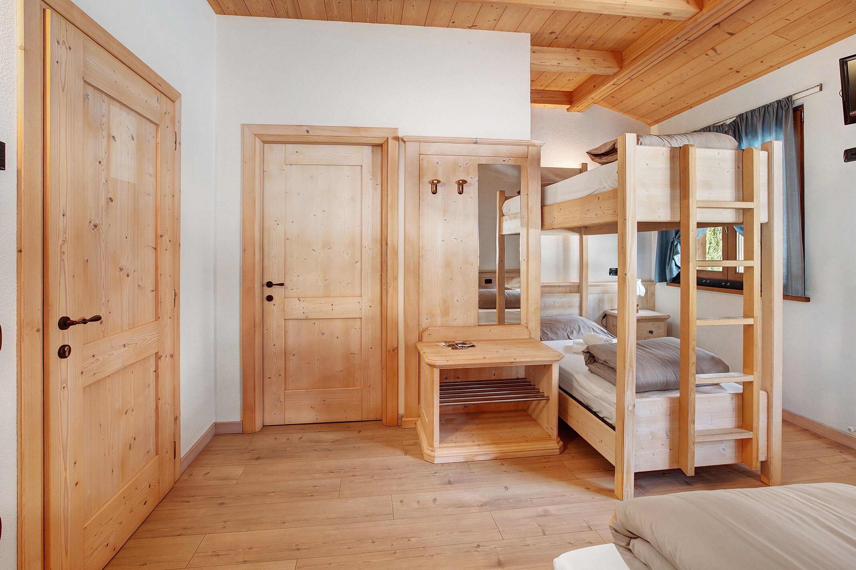 Ein Zimmer mit Holzboden, Stockbetten, einem Schreibtisch und einem Kleiderschrank.