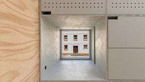 Quarto pequeno com vista para um edifício pela janela.