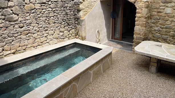 A stone-walled spa area with a rectangular hot tub and a bench. - House in the heart of the village (Cornillon)