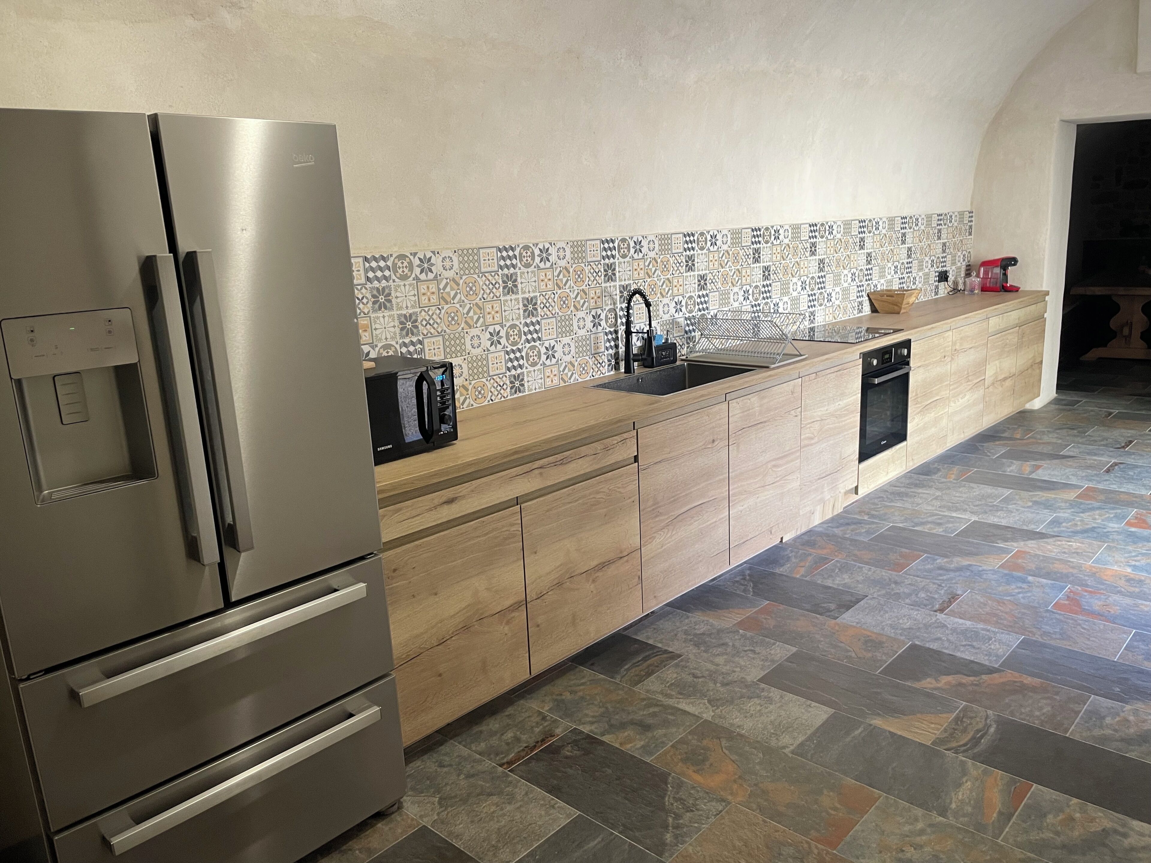 Una cocina moderna con un refrigerador de acero inoxidable, un lavavajillas integrado y un salpicadero con diseño.