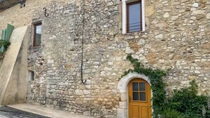 A stone building with a wooden door, a small window, and a number '9' sign. - House in the heart of the village (Cornillon)