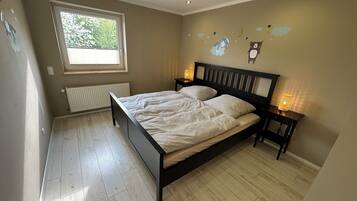 Un dormitorio con cama, ventana, radiador y adornos en la pared.