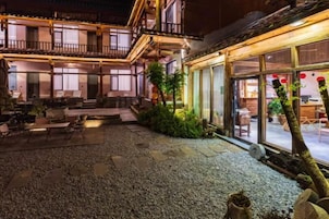 Um pátio com assentos, um edifício com varanda e um restaurante com mesas ao ar livre.