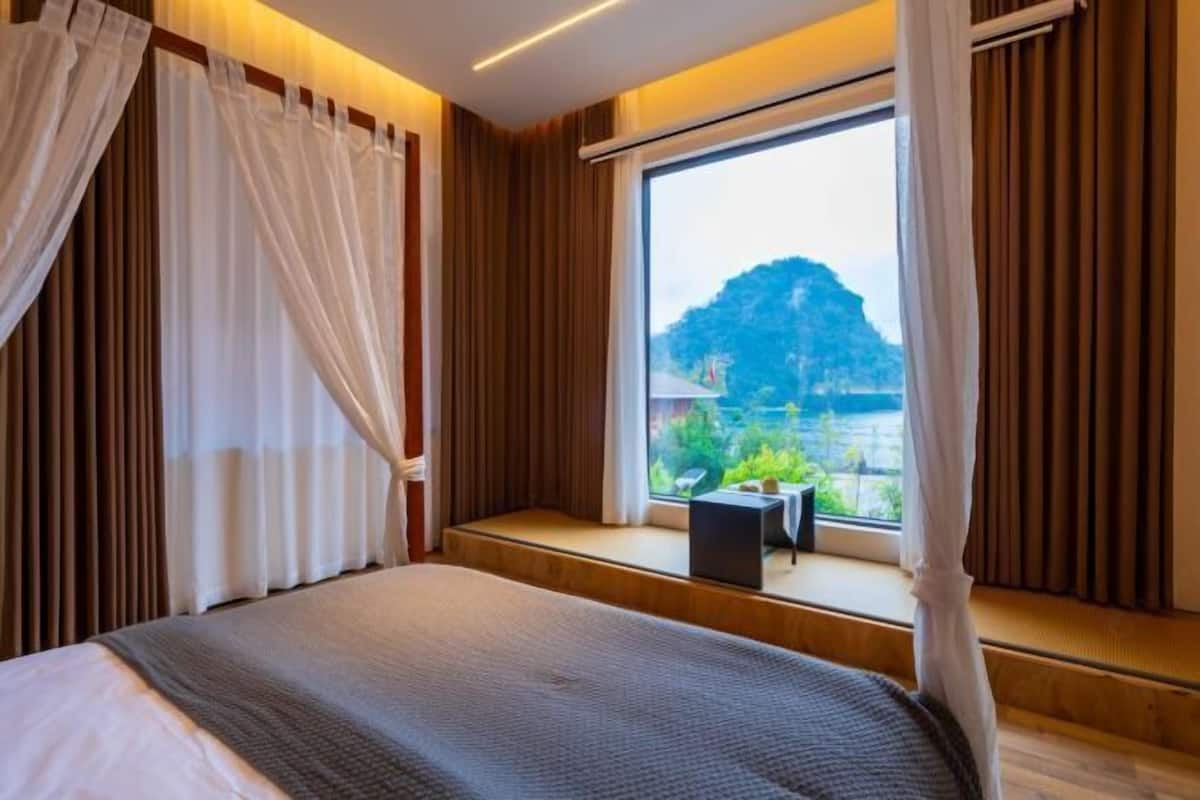 Quarto com uma janela grande, uma cama e cortinas.