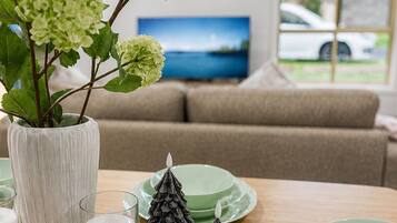 A dining table with green plates, a white vase with green flowers, and two pinecone decorations.
