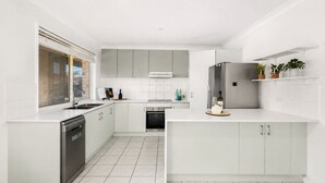 Eine moderne Küche mit weißen Schränken, einem Geschirrspüler, einem Einbauofen und einem Kühlschrank.