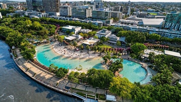 Ein Küstenresort mit zwei großen Schwimmbecken, einer Promenade und moderner Architektur im Hintergrund.