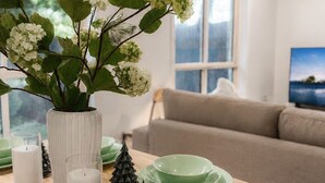 Ein Essbereich mit einem Holztisch, gedeckt mit grünen Tellern und einer Vase mit weißen Blumen.