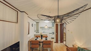 A modern interior with a dining area, kitchen, and staircase. - JS xiaozhai・yuishima (Osaka)