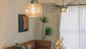 A modern living room with a brown leather sofa, a large pendant light, a floor lamp, and a potted plant. - JS xiaozhai・yuishima (Osaka)