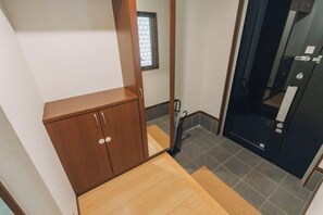 A room with a wooden cabinet, a small window, and a door leading to a bathroom. - JS xiaozhai・yuishima (Osaka)