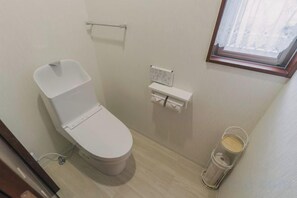 A small bathroom with a toilet, a towel rack, a window, and a trash bin. - JS xiaozhai・yuishima (Osaka)