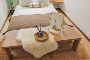 A bedroom with a bed, bedside table, mirror, and a small plant. - JS xiaozhai・yuishima (Osaka)