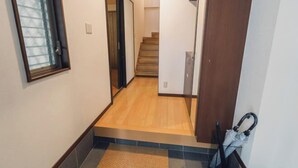 A hallway with a wooden floor, a door, and a window with blinds. - JS xiaozhai・yuishima (Osaka)