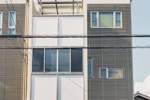 A multi-story building with horizontal siding and multiple windows. - JS xiaozhai・yuishima (Osaka)