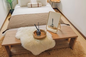 A neatly arranged bedroom with a bed, a wooden bedside table, a fluffy white rug, and a small wooden stool. - JS xiaozhai・yuishima (Osaka)