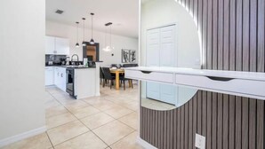 A modern kitchen with white cabinets, a dining area with a table and chairs, and a mirrored backsplash.