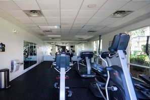 A gym with cardio machines, mirrors, and a windowed wall. - Cozy, Perfect for Families, Hot Tub & Grill - 3013 (Kissimmee)