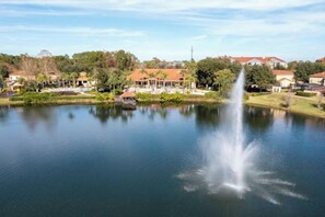 A tranquil lake with a fountain, surrounded by residential buildings and greenery. - Cozy, Perfect for Families, Hot Tub & Grill - 3013 (Kissimmee)