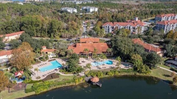 An aerial view of a residential area with houses, a swimming pool, and a lake.
