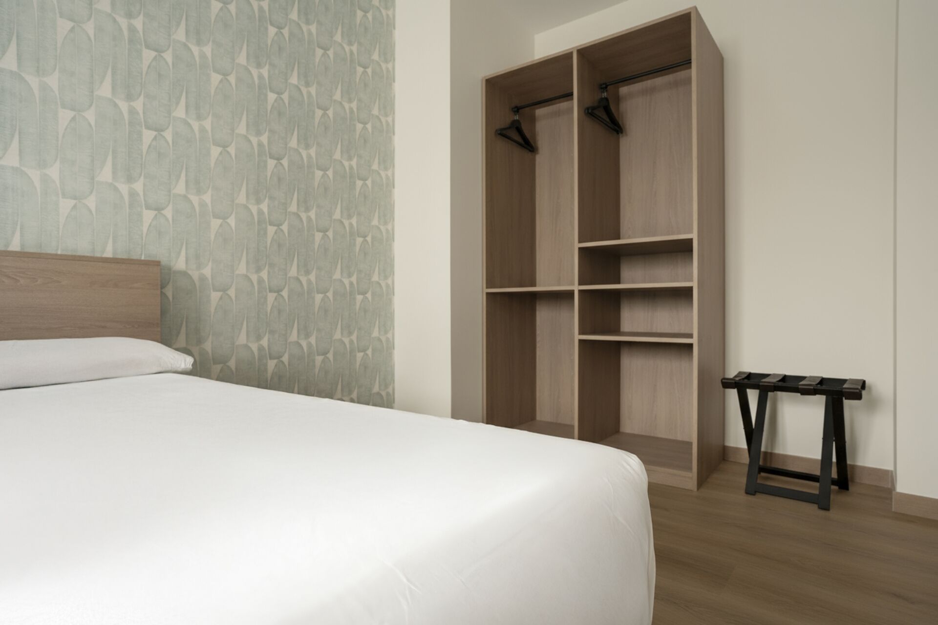 Een slaapkamer met een bed, een kledingkast en een kleine tafel.