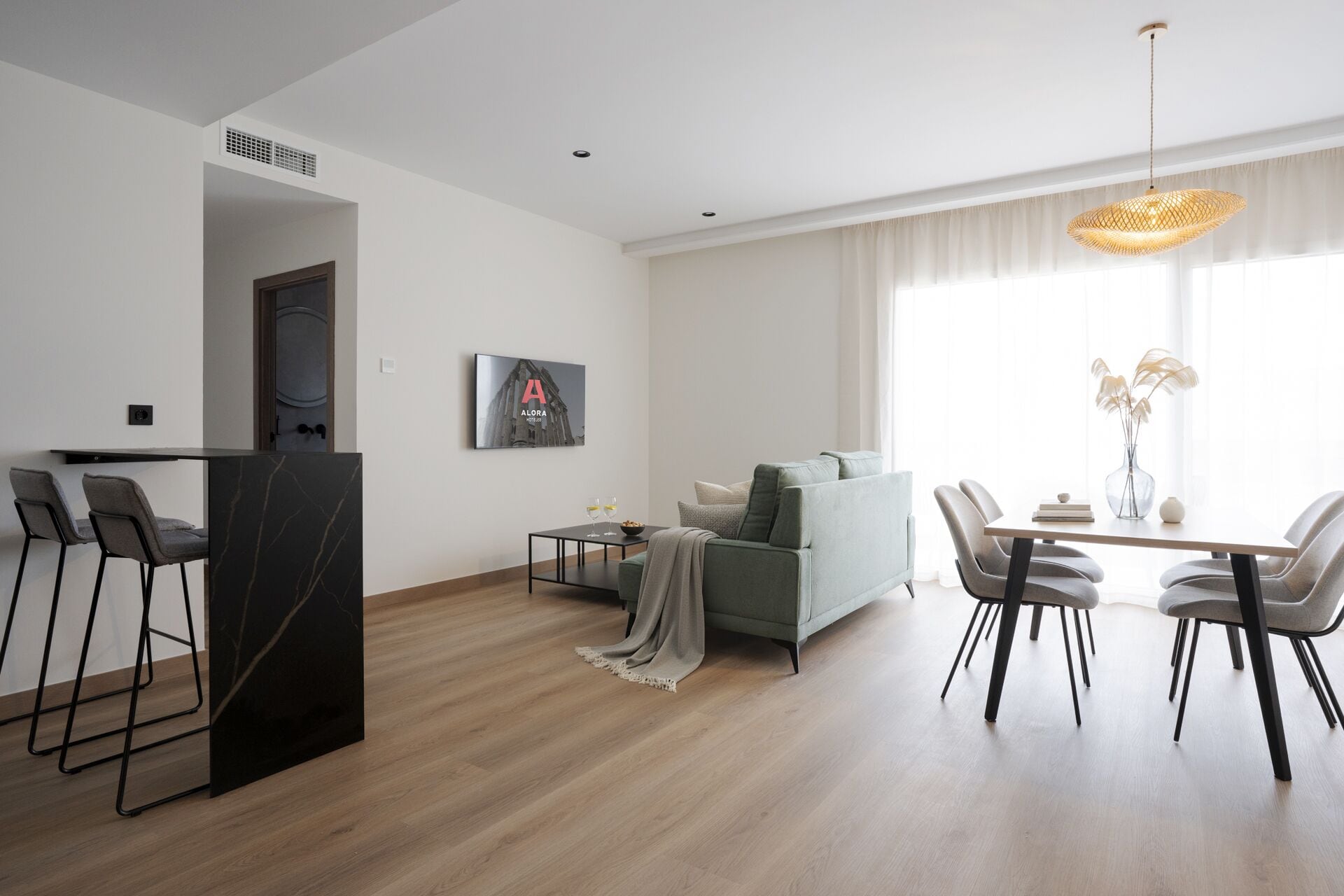 Een moderne woonkamer met een eethoek, een bank, een salontafel en een kroonluchter.