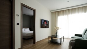 A hotel room with a bed, a desk, a chair, and a large window with curtains. - Alora Apartamentos Mérida (Mérida)