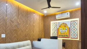 A modern living room with a sofa, a coffee table, and a ceiling fan. - Darpan Nikunj Rubystone Express (Vrindavan)