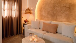 Een moderne woonkamer met een witte bank, een ronde salontafel met kaarsen en een decoratieve wand.