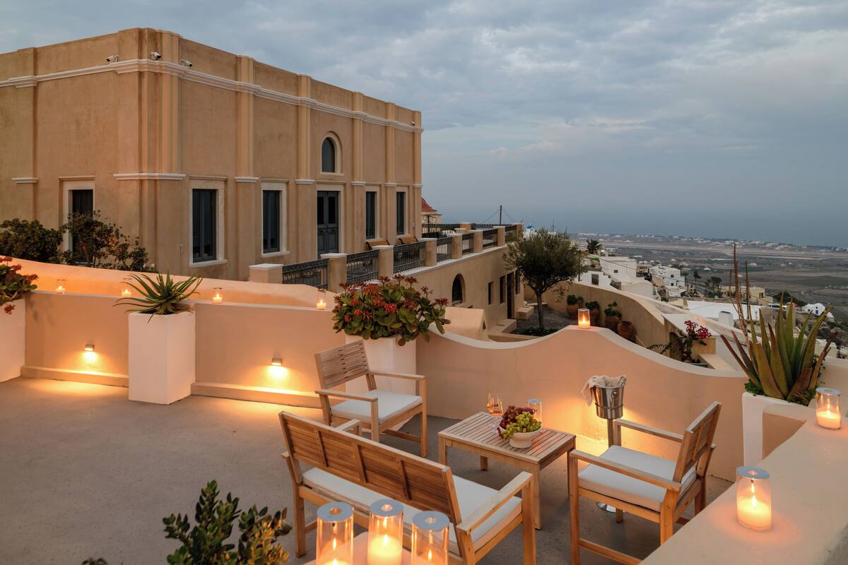 Eine Dachterrasse mit Außenmöbeln, Kerzen und Blick auf die Stadtlandschaft.