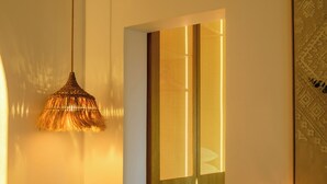 Een moderne kamer met een bank, een hanglamp en een houten garderobe met verlichte panelen.