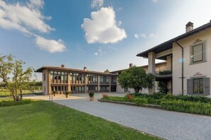 A modern building with a glass facade, a gravel driveway, and a well-maintained lawn. - Appartamento Brut (Iseo)