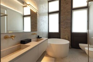 A modern bathroom with a large bathtub, two sinks, and a large mirror. - Appartamento Brut (Iseo)