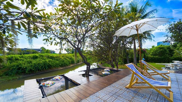 Eine Holzterrasse mit Pool, Liegestühlen und Sonnenschirm.