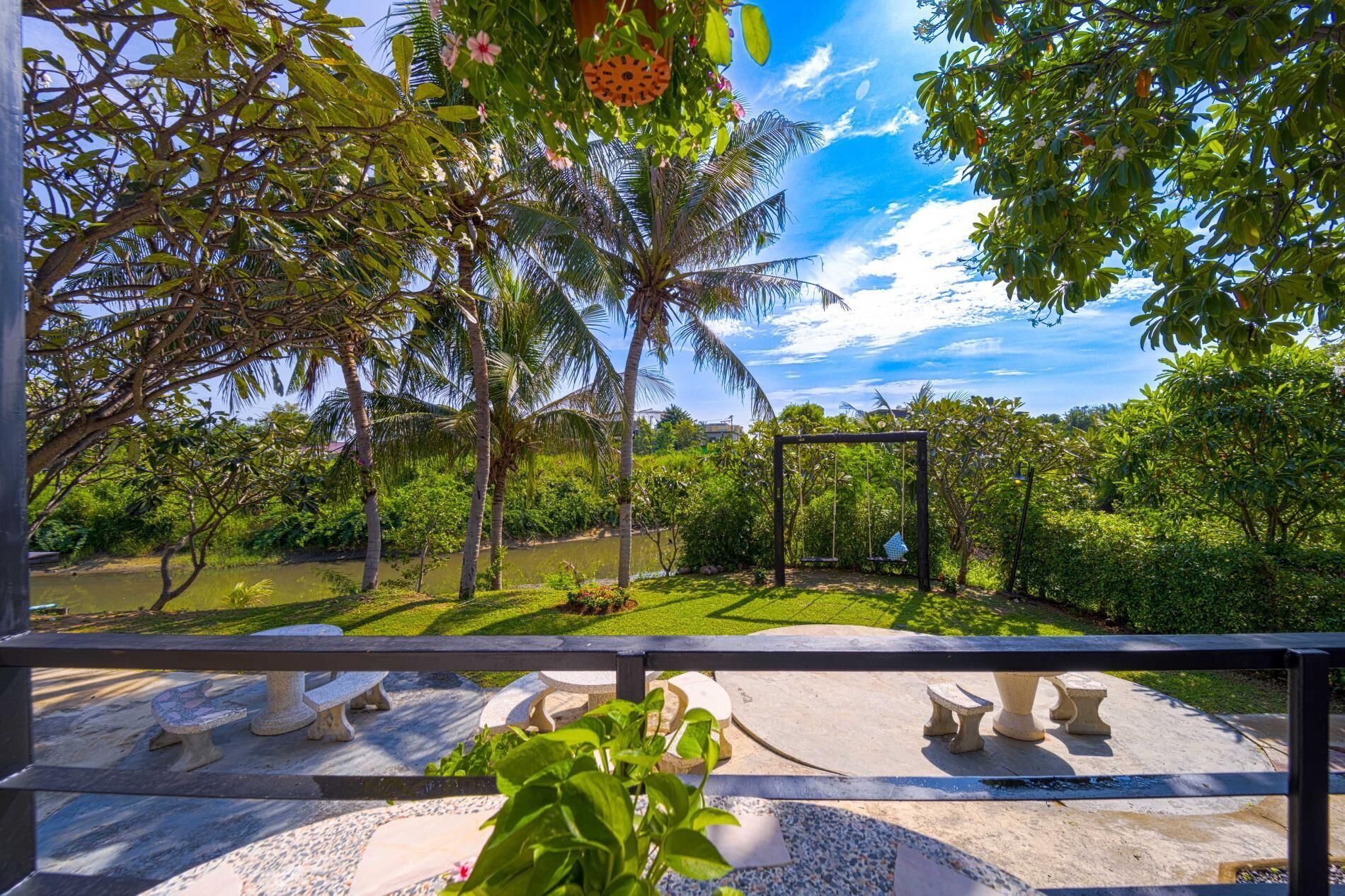 A garden with a swing set, stone benches, and a pond.