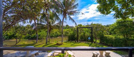 A garden with a swing set, stone benches, and a pond.
