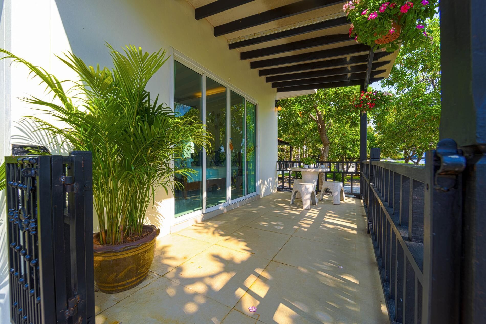 A covered outdoor area with a potted plant, a table, and chairs.