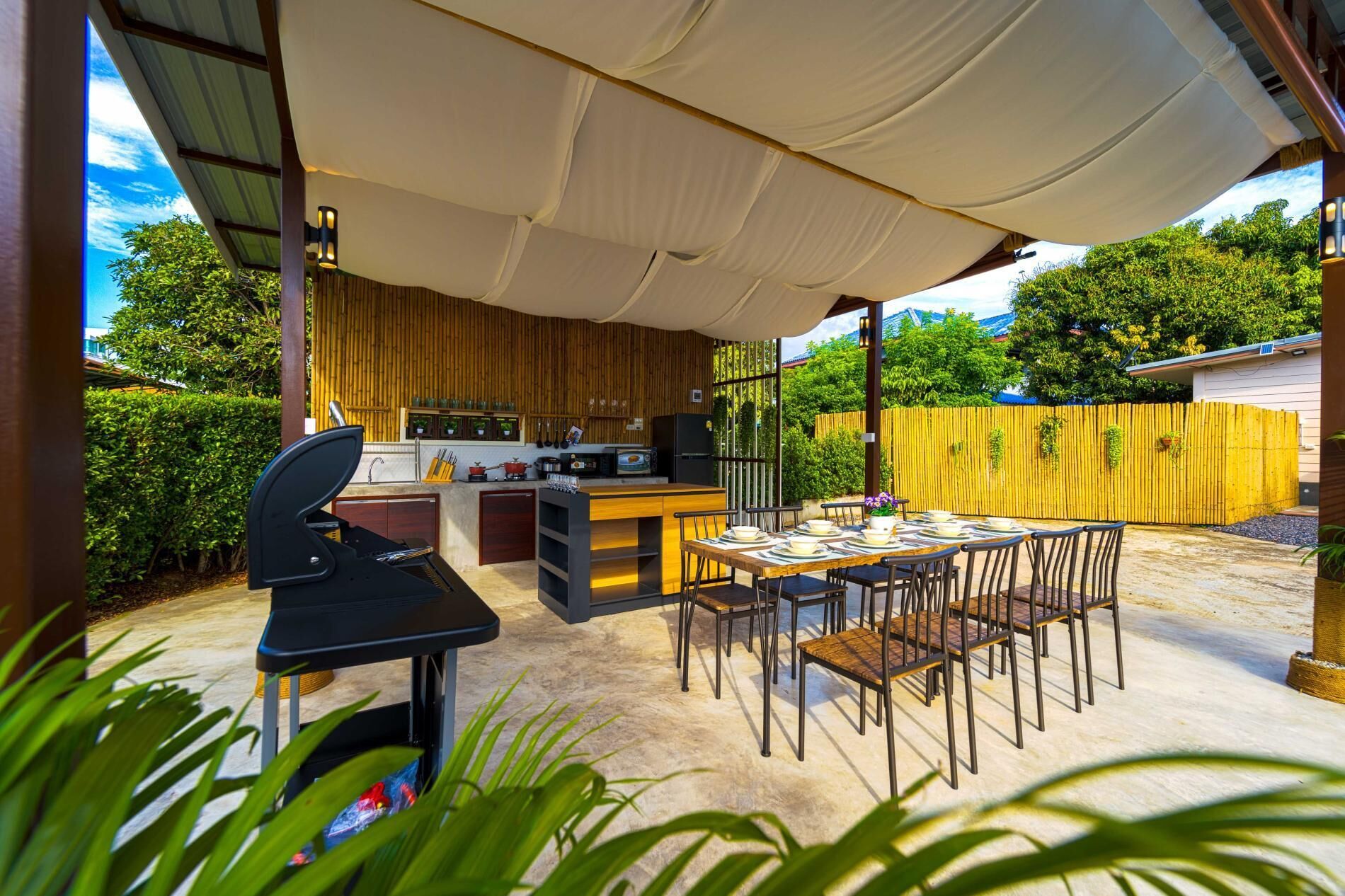 An outdoor kitchen area with a grill, dining table, and chairs.