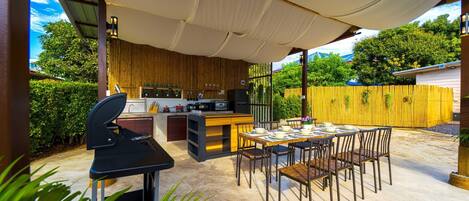 An outdoor kitchen area with a grill, dining table, and chairs.