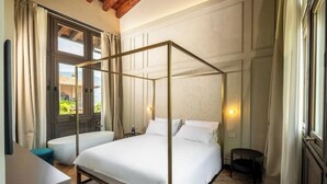 A four-poster bed in a room with a wooden ceiling, a large window, and a view of greenery outside. - Suite..... (Iseo)